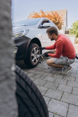 Adam araç gereçleri kullanarak yol kenarında lastik değiştiriyor, araç krikoda kaldırılıyor. Araba tamiri, bakım, arıza yardımı ve gerçek hayat durumları kavramı. Yüksek kalite fotoğraf