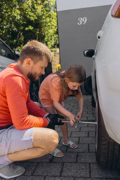 Küçük bir kız babasının arabasının lastiklerini değiştirmesine yardım eder. Yürekten bir bağ kurma deneyimi yaratır. Yüksek kalite fotoğraf