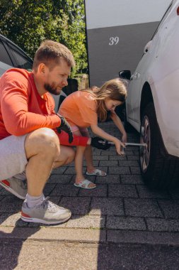 Küçük bir kız babasının arabasının lastiklerini değiştirmesine yardım eder. Yürekten bir bağ kurma deneyimi yaratır. Yüksek kalite fotoğraf
