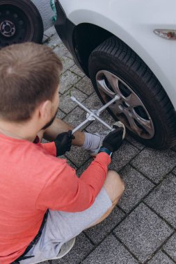 Adam araç gereçleri kullanarak yol kenarında lastik değiştiriyor, araç krikoda kaldırılıyor. Araba tamiri, bakım, arıza yardımı ve gerçek hayat durumları kavramı. Yüksek kalite fotoğraf