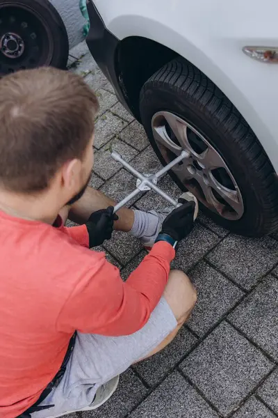 Adam araç gereçleri kullanarak yol kenarında lastik değiştiriyor, araç krikoda kaldırılıyor. Araba tamiri, bakım, arıza yardımı ve gerçek hayat durumları kavramı. Yüksek kalite fotoğraf