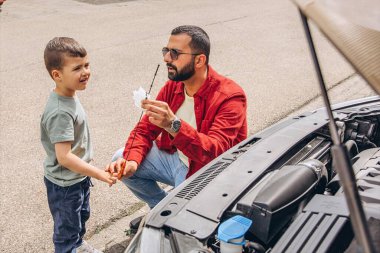 Baba ve oğulları kaputu açık bir şekilde araba tamir ediyorlar. İçten bir bağ kurma, babalık, ebeveynlik, takım çalışması ve öğrenme anı. Babalar Günü 'nü ortak tecrübelerimizle kutluyoruz. Yüksek kalite fotoğraf