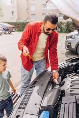 Baba ve oğulları kaputu açık bir şekilde araba tamir ediyorlar. İçten bir bağ kurma, babalık, ebeveynlik, takım çalışması ve öğrenme anı. Babalar Günü 'nü ortak tecrübelerimizle kutluyoruz. Yüksek kalite fotoğraf