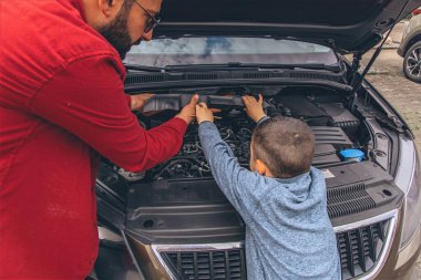 Baba ve oğulları kaputu açık bir şekilde araba tamir ediyorlar. İçten bir bağ kurma, babalık, ebeveynlik, takım çalışması ve öğrenme anı. Babalar Günü 'nü ortak tecrübelerimizle kutluyoruz. Yüksek kalite fotoğraf