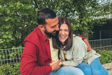 Mutlu çift gülerken erkek arkadaş kız arkadaşını parkta gıdıklıyor. Sevgi dolu bir an, bağ kurma ve dışarıda kaygısız bir mutluluk, aşkı, bağlantıyı ve gerçek duyguları yakalamak. Yüksek kalite fotoğraf