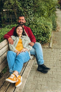 Irklar arası çift parkta birlikte oturur, gülümser ve huzurlu bir anın tadını çıkarırlar. Açık havada çeşitliliği, birliği ve mutluluğu yakalayan sıcak, sevgi dolu bir bağ. Yüksek kalite fotoğraf