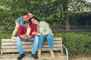 Mutlu çift dışarıda bir bankta oturuyor, gülümsüyor ve birbirlerine sarılıyorlar. Neşeli, sevecen bir an. Sevgiyi, bağlantıyı ve tasasız birlikteliği doğal ortamında yakalıyor. Yüksek kalite fotoğraf