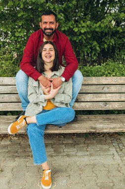 Irklar arası çift parkta birlikte oturur, gülümser ve huzurlu bir anın tadını çıkarırlar. Açık havada çeşitliliği, birliği ve mutluluğu yakalayan sıcak, sevgi dolu bir bağ. Yüksek kalite fotoğraf