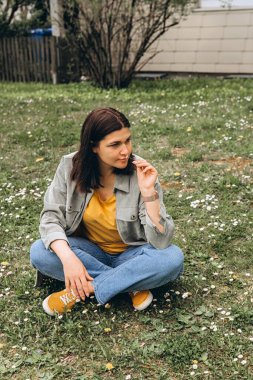 Genç bir kadın çimenlerde oturur, güneşli bir günde çiçeğin kokusunu alır. Doğadaki sakin bir an, sağlıklı olmayı, temiz havayı ve polen reaksiyonu belirtisi olmayan alerjisiz yaşam tarzını simgeliyor. Yüksek kalite fotoğraf