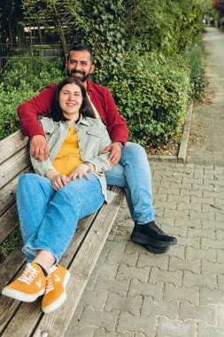 Irklar arası çift parkta birlikte oturur, gülümser ve huzurlu bir anın tadını çıkarırlar. Açık havada çeşitliliği, birliği ve mutluluğu yakalayan sıcak, sevgi dolu bir bağ. Yüksek kalite fotoğraf