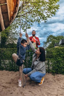 Çocuk parkında birlikte oynayan 6 yaşında bir çocukla çok uluslu bir aile. Aktif ebeveynlik yapan ebeveynler, açık hava aktiviteleri ve oyun yoluyla güçlü çocuk ilişkileri kurarlar. Yüksek kalite fotoğraf