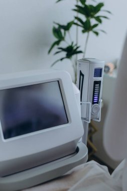 Modern bir güzellik kliniğinde, endosfer terapi makinesinin yanında oturan beyaz elbiseli bir kadın. Vücut bakımı, anti-selülit tedavisi, zayıflatma ve donanım masajı kavramı. Yüksek kalite fotoğraf