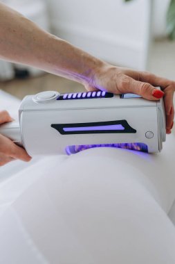 Bir güzellik kliniğinde anti-selülit terapi seansı. Beyaz elbiseli bir kadın zayıflatma, şekillendirme ve lenfatik drenaj için donanım vücut masajı görüyor. Yüksek kalite fotoğraf