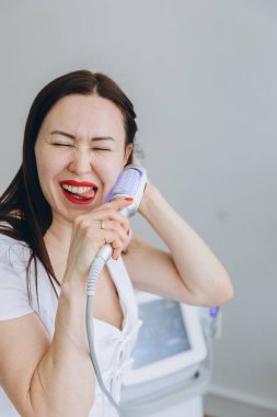 Gülümseyen kadın yüz masajı terapisinden zevk alıyor. Kozmetik kliniğinde modern güzellik teknolojisi kullanarak yaşlanmayı önleyici bir yüz tedavisi. Yüksek kalite fotoğraf