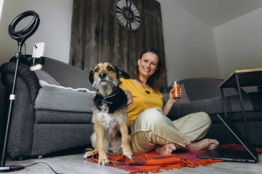 Köpeği ve bir bardak taze meyve suyuyla evde dinlenen bir kadın. Uzaktan çalışma, sağlıklı yaşam tarzı, evcil hayvan arkadaşlığı ve rahat ev atmosferi kavramı. Yüksek kalite fotoğraf