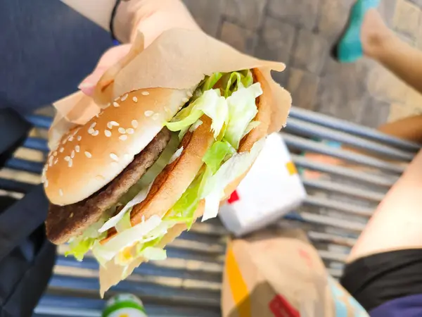 delicious juicy burger in hands, sesame bun, lettuce, meat cutlet