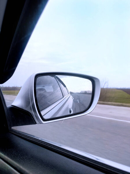 view from the window of a gray car moving on the road to the front car mirror and road movement speed track trip road trip