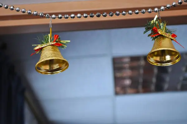 iki, küçük, altın, yeni yıl, Noel, çanlar, turuncu bir duvarda gümüş bir çelenk, yeni yıl süslemeleri, Noel süslemeleri, Noel çanları, ev yapımı Noel süslemeleri, el yapımı