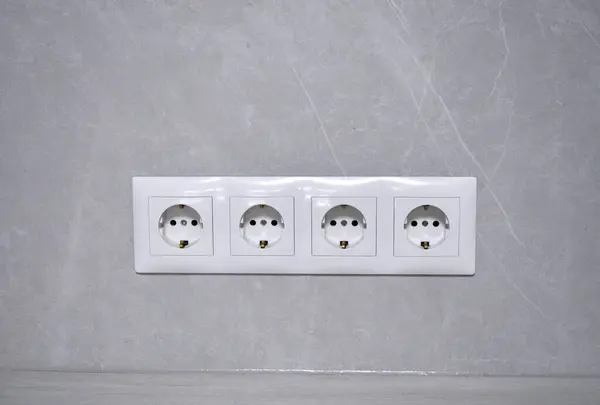 Beyaz prizler bloğu, 220, 110 volt, gri bir duvara elektrik.