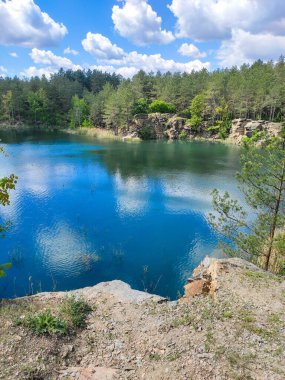 Bir taş ocağında mavi bir göl, ormanla çevrili bir kanyonda uçurum, köknar ağaçları, ağaçlar, dağ 