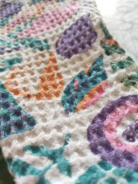 Parlak renkli desenli waffle kumaşının yakın çekim dokusu. turuncu, yeşil, leylak ve pembe, samimi ve neşeli bir ruh hali. Arka plan bulanık, kumaş deseni bulanık..