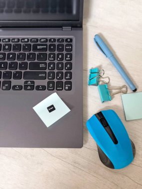 Laptoplu iş yeri, mavi kablosuz fare, zarflar, defter, ofis masası, ahşap masadaki yapışkan notlar. İş, planlama, uzaktan çalışma konsepti, serbest çalışma, eğitim