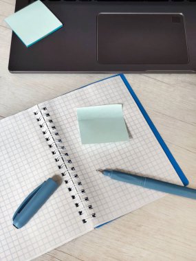 Yaratıcı konsept fotoğraf ve mavi kalemli kare bir deftere yapışkan bir not. Fikirlerin, planlamanın, yazmanın ya da dijital ilhamın sembolü. ofis masası çalışma yeri