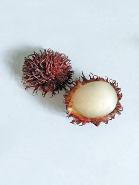 Beyaz arka planda taze rambutan meyvesi. Bir tam bir buçuk açık, şeffaf et gösteriyor. Egzotik tropikal meyve.