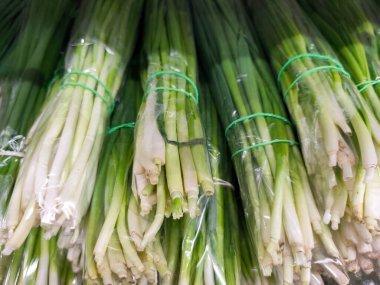 Taze yeşil soğanlar paketlenmiş ve markette plastiğe sarılmış. Sağlıklı mevsimlik sebzeler yemek ve salata için hazır. Organik gıda ve vejetaryen malzeme.