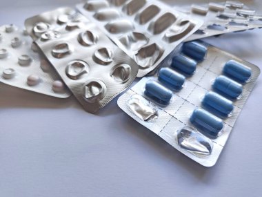 Beyaz arka planda mavi ve beyaz haplı Blister paketleri kullanıldı. İlaç, tedavi, ilaç ürünleri bir pakette. İlaç tedavisi, hastalık...