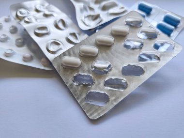 Beyaz arka planda mavi ve beyaz haplı Blister paketleri kullanıldı. İlaç, tedavi, ilaç ürünleri bir pakette. İlaç tedavisi, hastalık...