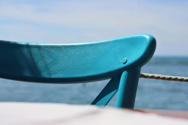 Closeup of the retro chair back detail. Beautiful wooden texture of turquoise painted vintage chair back. Scenic blue sky and sea view on the background.  Sunny summer day on Adriatic. Selective focus