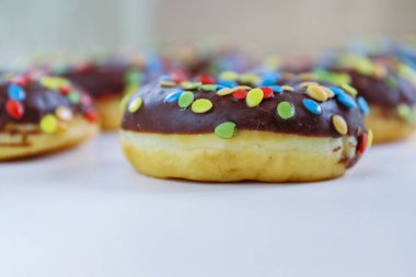 Kahverengi çikolatalı donut seti beyaz arka planda izole edilmiş ukalalarla dekore edilmiş. Kızarmış hamur şekeri, tatlı yiyecekler, çikolata kaplı tatlı atıştırmalıklar ve şekerler. Seçici odak