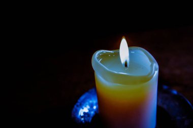 Ahşap masada mum yaktı. Mum tutacağında yanan mum. Yanan ışık. Sıcak ateş. Sıcak bir atmosfer. Seçici odaklanma. Pencereden gelen ışık.