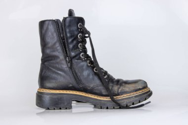 Çok yıpranmış bir botun yan görünüşü. Eski, kırık siyah deri dantelli yüksek çizme. Moda ayak bileği ayakkabısı. Şık kadınların erkek üniforması. Ayakkabı bağcıklı Grunge çizmesi. beyaz arkaplanda izole