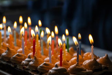 Evdeki doğum günü partisinde 15 tane renkli mum yakın. Büyük ev yapımı çikolatalı pasta, krema ve kremayla süslenmiş. Kutlama konsepti. Seçici odak.