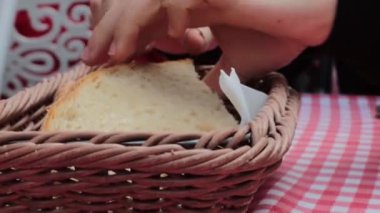 Bratislava 'daki Grand Mothers Slovakya restoranında yemek yiyeceğiz. Genç kadın hasır sepetten bir parça beyaz ekmek alıyor. Onu eliyle parçalıyor ve bir parçasını yiyor.