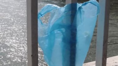 Budapeşte 'de Donau nehrinin üzerindeki Elisabeth köprüsünün korkuluklarında asılı duran mavi plastik torba. Şehirde çöp var. Çevre kirliliği kavramı. Ekolojik felaket, felaket. Seçici odak