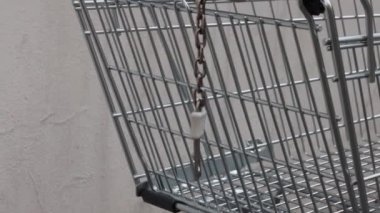 Mağazanın arka bahçesinde kaldırım taşı yolundaki kirli beton duvarın yanında duran terk edilmiş, boş, mavi saplı bir alışveriş arabası. Kırpılmış. Kapatın. Uzayı kopyala Seçici odak.