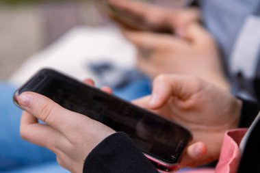 Cep telefonu ekranını işaret et. Mesaj atan kişi, hippi dokunuşlu akıllı telefon ekranı. Kız elleri kaydırmalı sohbeti tutuyor. Yaz parkı. Kapatın. Uzayı kopyala Seçici odak