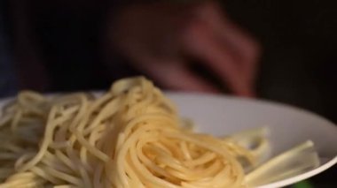 Kadın tencerede ya da tavada sıcak spagetti ya da makarna servis ediyor ve tabağa beyazı koyuyor. Akşamları aile yemeği.