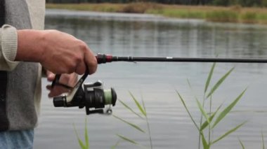 Yakın çekim ekipmanları ve tanınmayan sinek avcılarının elleri. Fisher olta makarasını döndürüyor. Yırtıcı balıkları taze suda avlarken bir adam halatta sallanıyor. Finlandiya 'da yaz