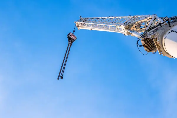 stock image Construction crane arm with hook with cable against clear blue sky background. Industrial equipment or tools. Copy space. Selective focus.