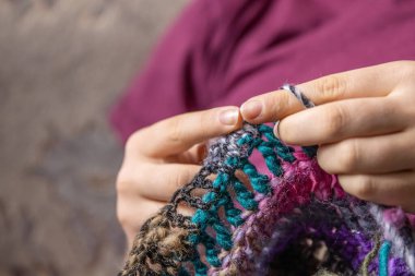 Ellerinde kanca ve yün iplik tutan genç bir bayan, el yapımı kazak, evde rahat zaman geçirmek için el işi hobisi, kraft sanatı ya da çiftçi pazarı için eşsiz ürünler yapıyor..