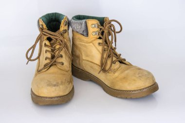 Güzel yansıma efektiyle beyaz parlak yüzeyde izole edilmiş bir çift eski sarı yürüyüş dantel botu. İkinci el turist yürüyüş ayakkabıları. Yan görüş. Uzayı kopyala Beyaz arkaplan.