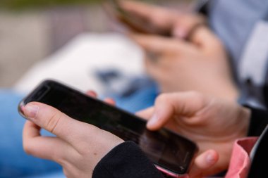 Cep telefonu ekranını işaret et. Mesaj atan kişi, hippi dokunuşlu akıllı telefon ekranı. Kız elleri kaydırmalı sohbeti tutuyor. Yaz parkı. Kapatın. Uzayı kopyala Seçici odak