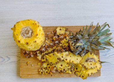 Freshly Peeled Pineapple with Top crown Removed and Skin Sliced on Wooden Cutting Board. Preparation, cleaning, cutting pineapple into pieces. clipart