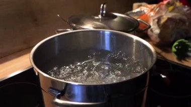 Fırının üstünde paslanmaz çelik bir tencerede kaynar su. Yemek ve mutfak rutini. Yemek hazırlama tüyoları, yemek tarifleri, mutfak teknikleri, özel dersler ve mutfak güvenliği ile ilgili. 4K video