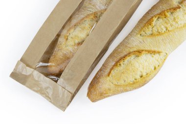 İki yeni pişmiş baget, biri kahverengi kese kağıdına sarılı, kağıt ambalajında çıtır çıtır ekmek kırıntıları olan Fransız ekmekleri. Beyaz bir arka planda izole edilmiş. - Yakın çekim. kırpma yolu ile