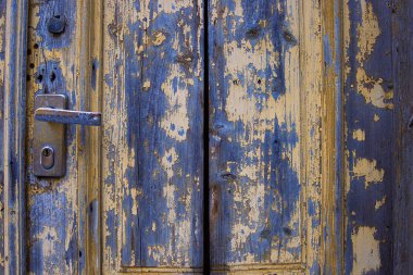 Metalik kilidi ve kapı kolu olan klasik bir kırsal kapı. Yırtık boya ve yıpranmış bir yüzeyi olan eski ahşap bir doku. Antika kapı kolu tasarımı. Yaratıcı projeler için fon. Boşluğu kopyala